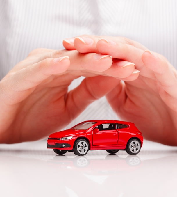 Hands keeping a toy car protected symbolizing car insurance