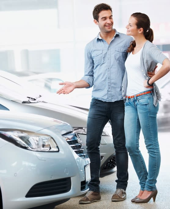A couple in front of 2 vehicles deciding on the second car loan