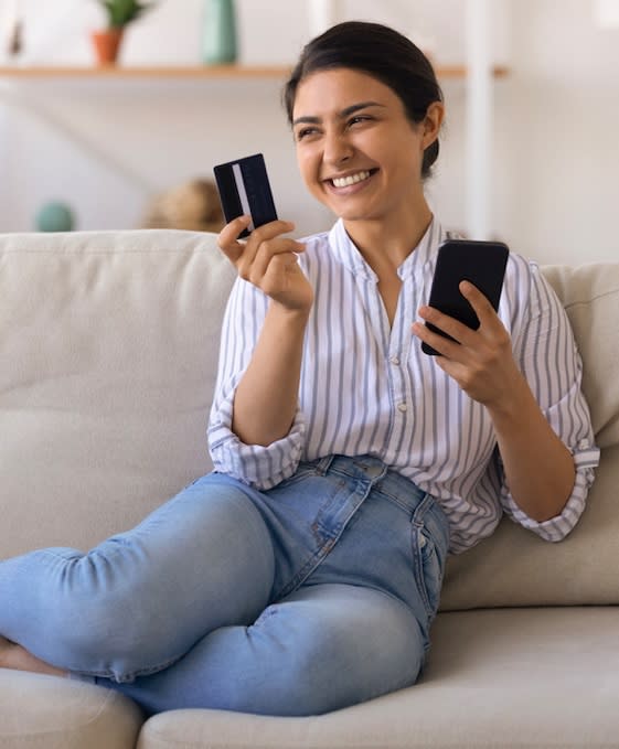 A smiling woman holding a credit card in her hand