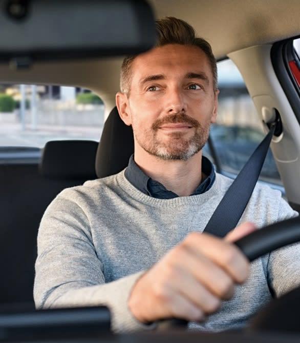 A photo of an adult man driving his car in the city