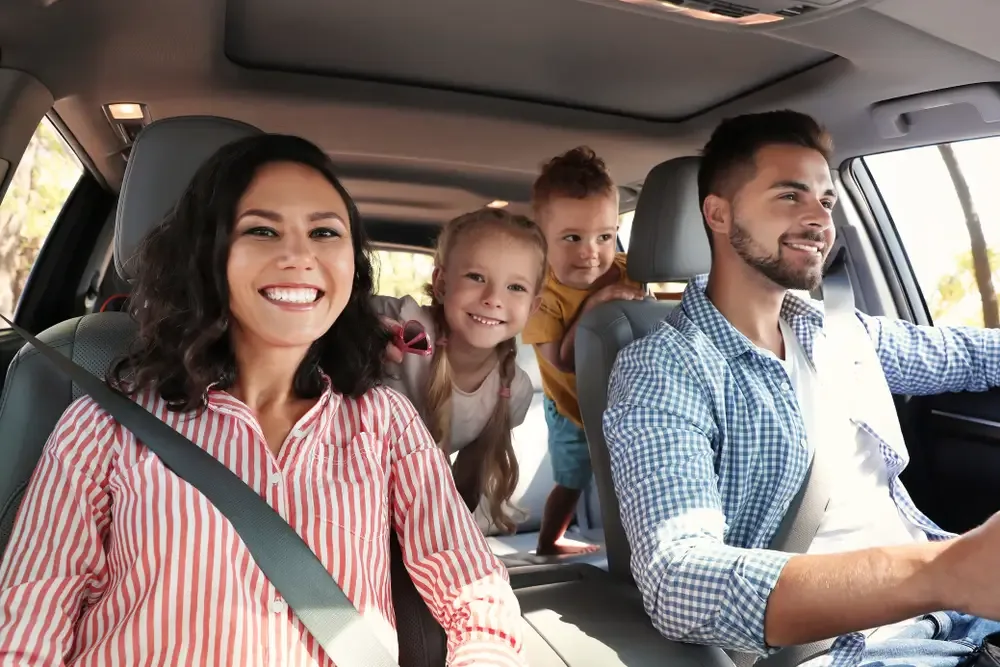 Family sitting inside a car driving in their refinanced car