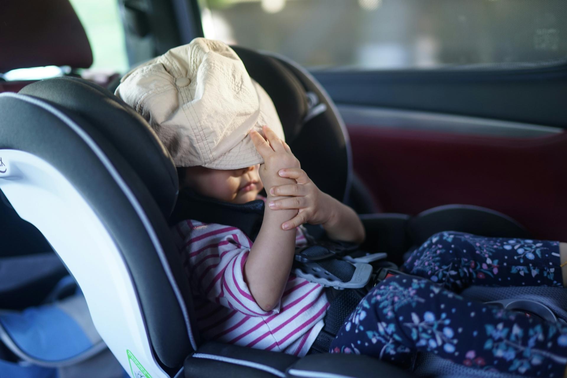 toddler in car seat with hat covering face