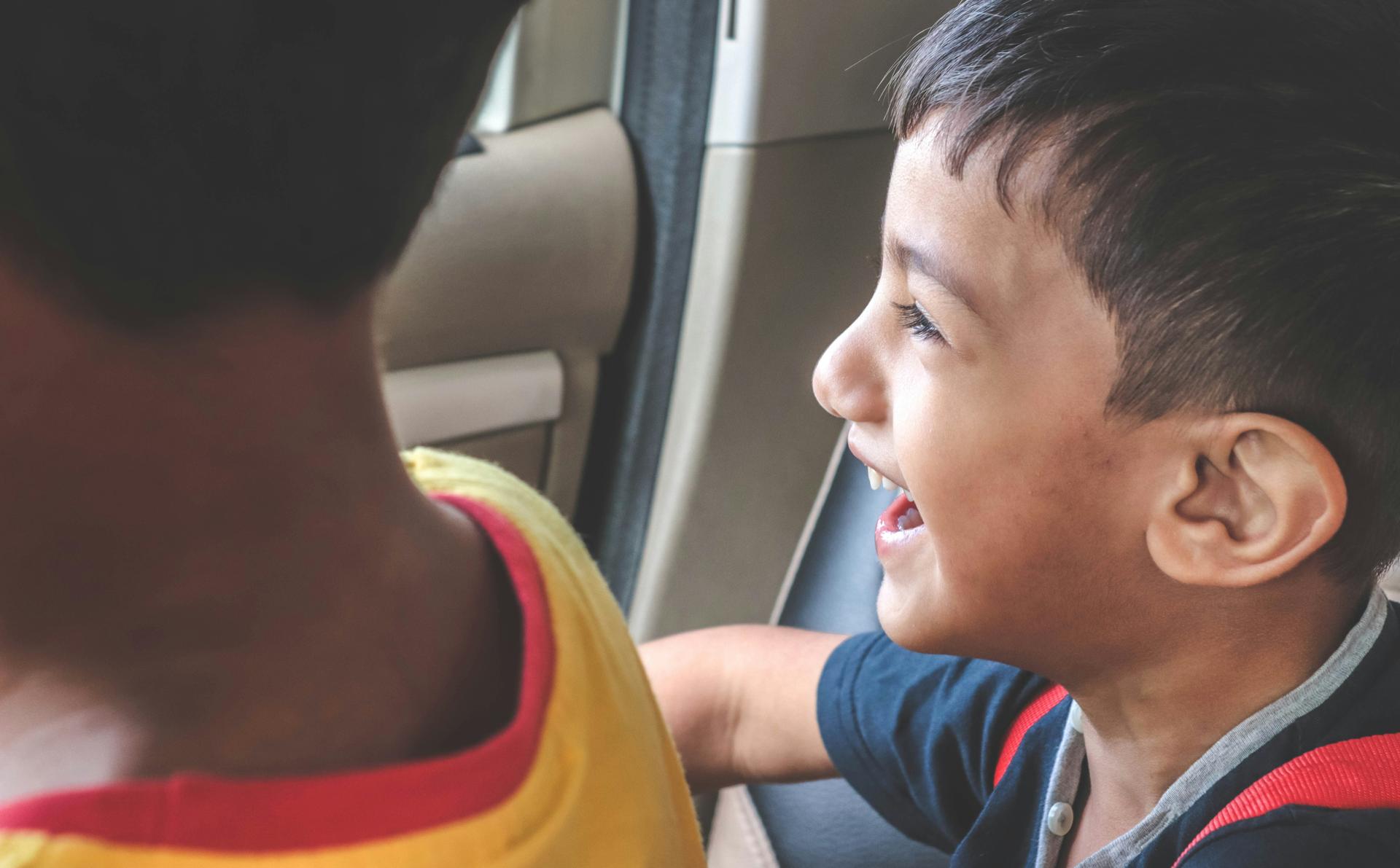 two young boys laughing in car backseat