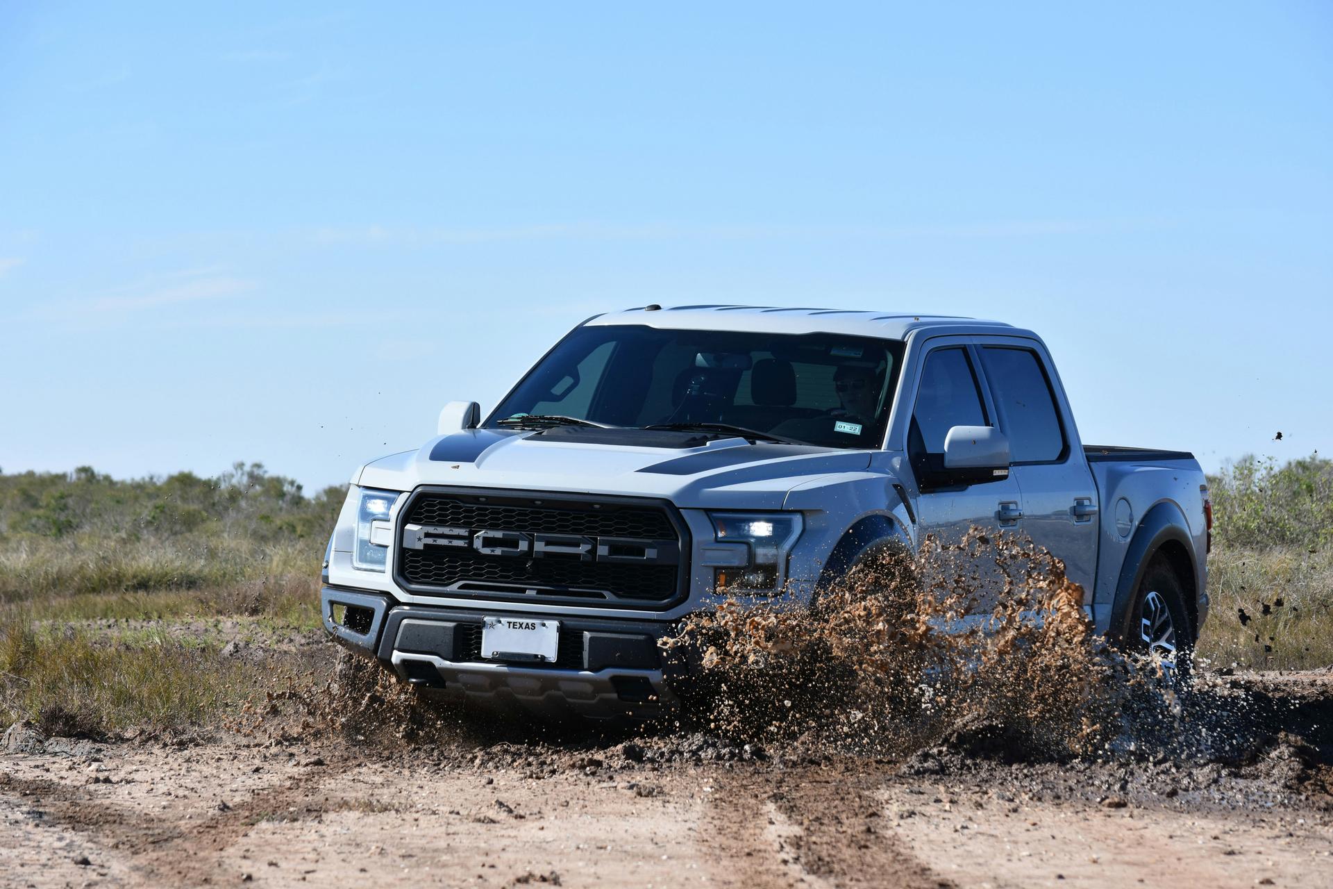 Silver Ford truck splashing through muddy water