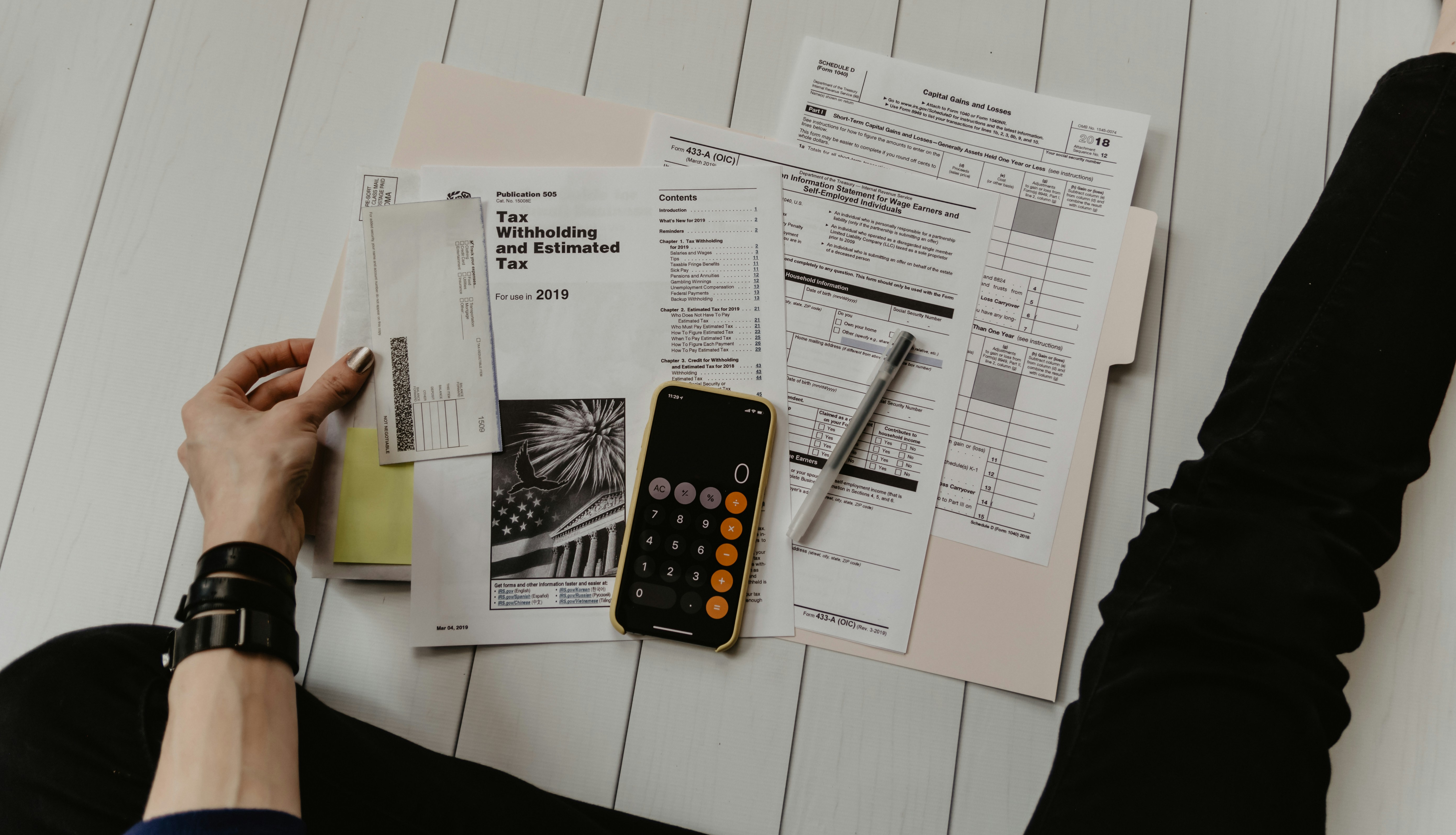 person doing their taxes on a white wood surface